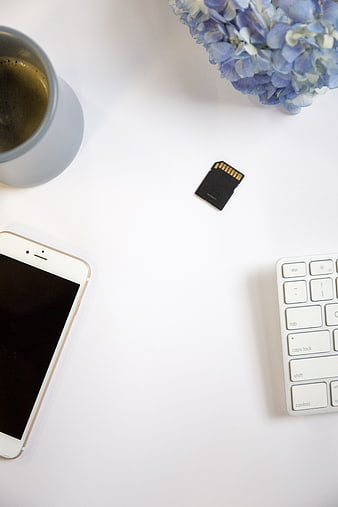 Minimalist workspace flat lay with smartphone, keyboard, and SD card