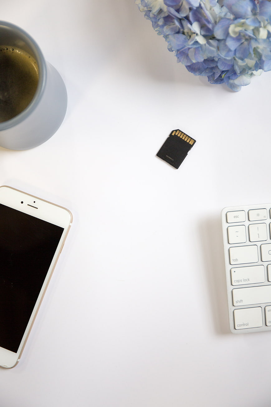 Minimalist workspace flat lay with smartphone, keyboard, and SD card