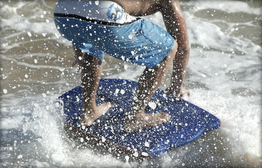 Surfer riding a wave on a blue bodyboard in the ocean