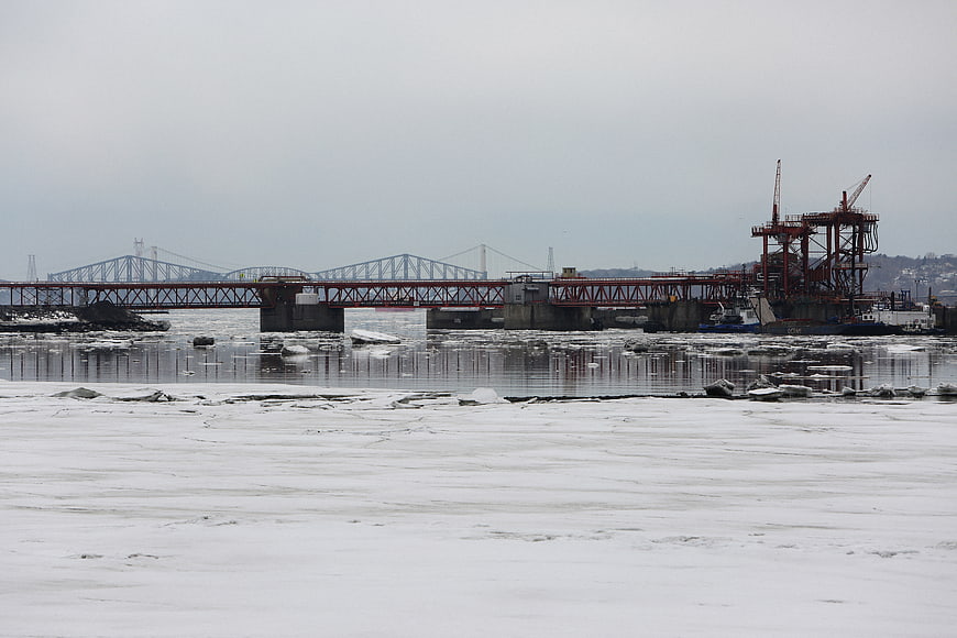 Frozen River with Industrial Bridge and Cranes in Winter