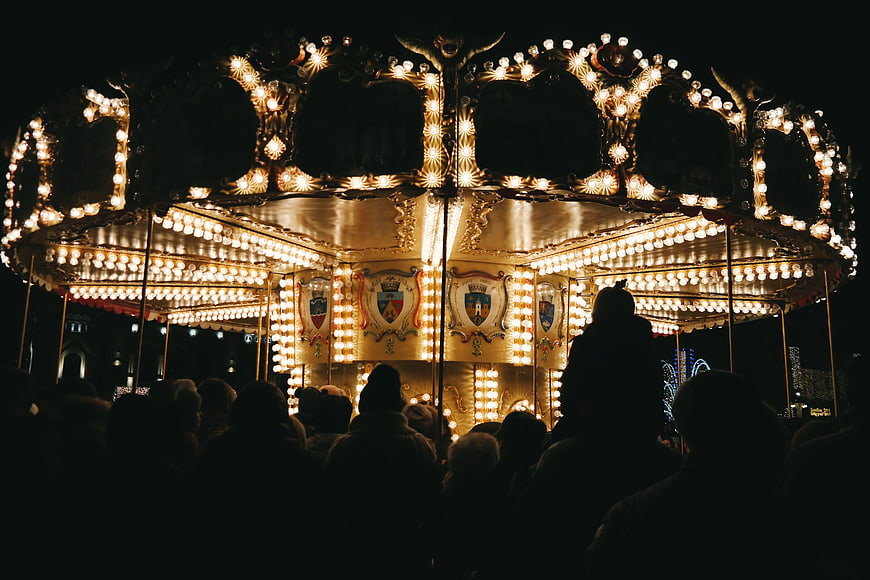Vintage Carousel Illuminated at Night with Crowd Silhouettes