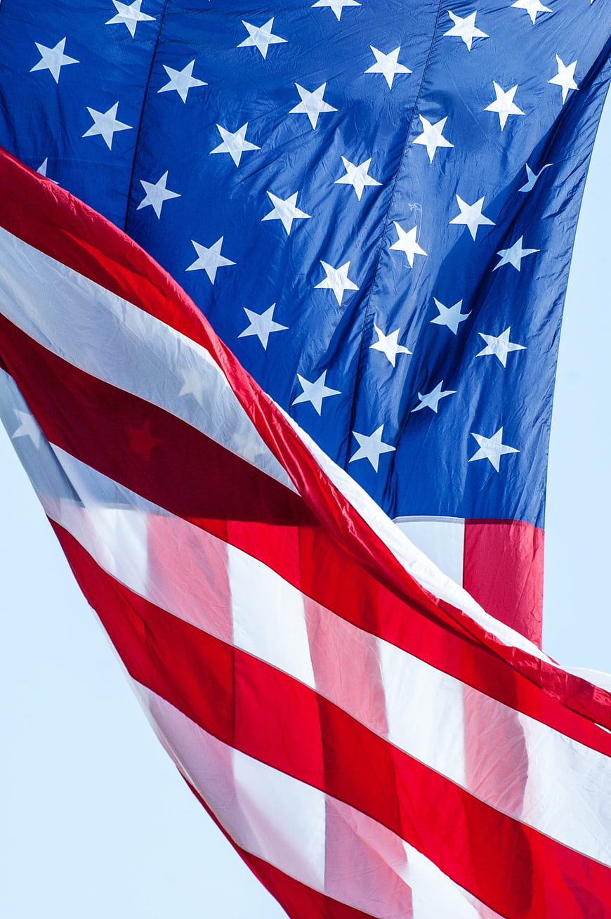 Close-up of waving American flag with stars and stripes against blue sky