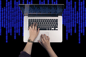 Hands typing on laptop with binary code background