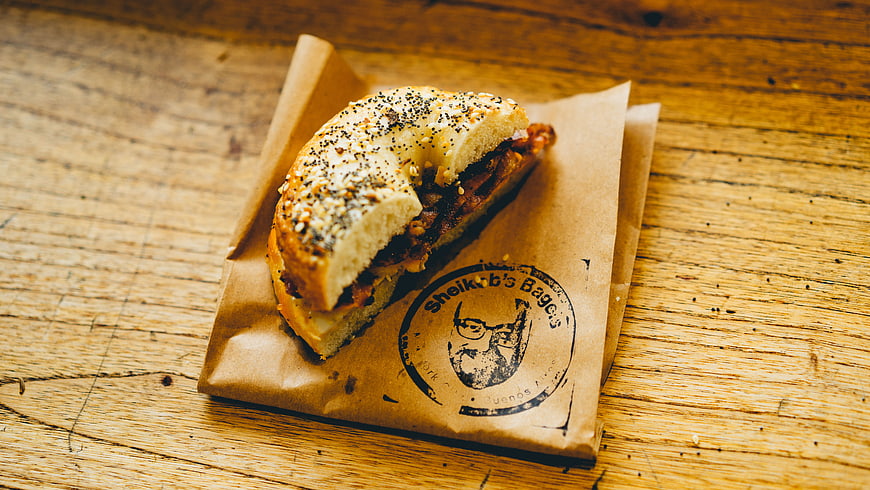 Bagel Sandwich on Brown Paper Wrapper on Wooden Table