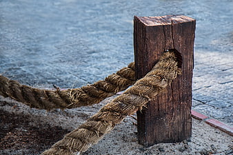Weathered Rope Tied to Wooden Post on Sandy Ground