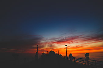 Silhouetted People on Pier at Vibrant Sunset