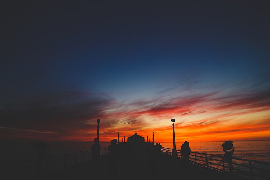 Silhouetted People on Pier at Vibrant Sunset