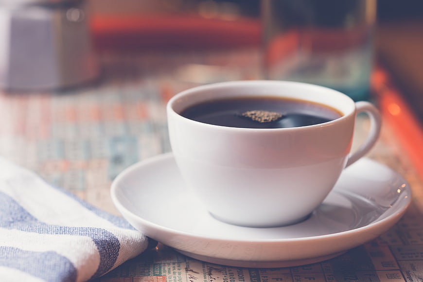 White Cup of Black Coffee on Newspaper Background