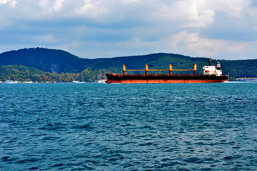 Large Cargo Ship Sailing on Blue Sea with Mountains