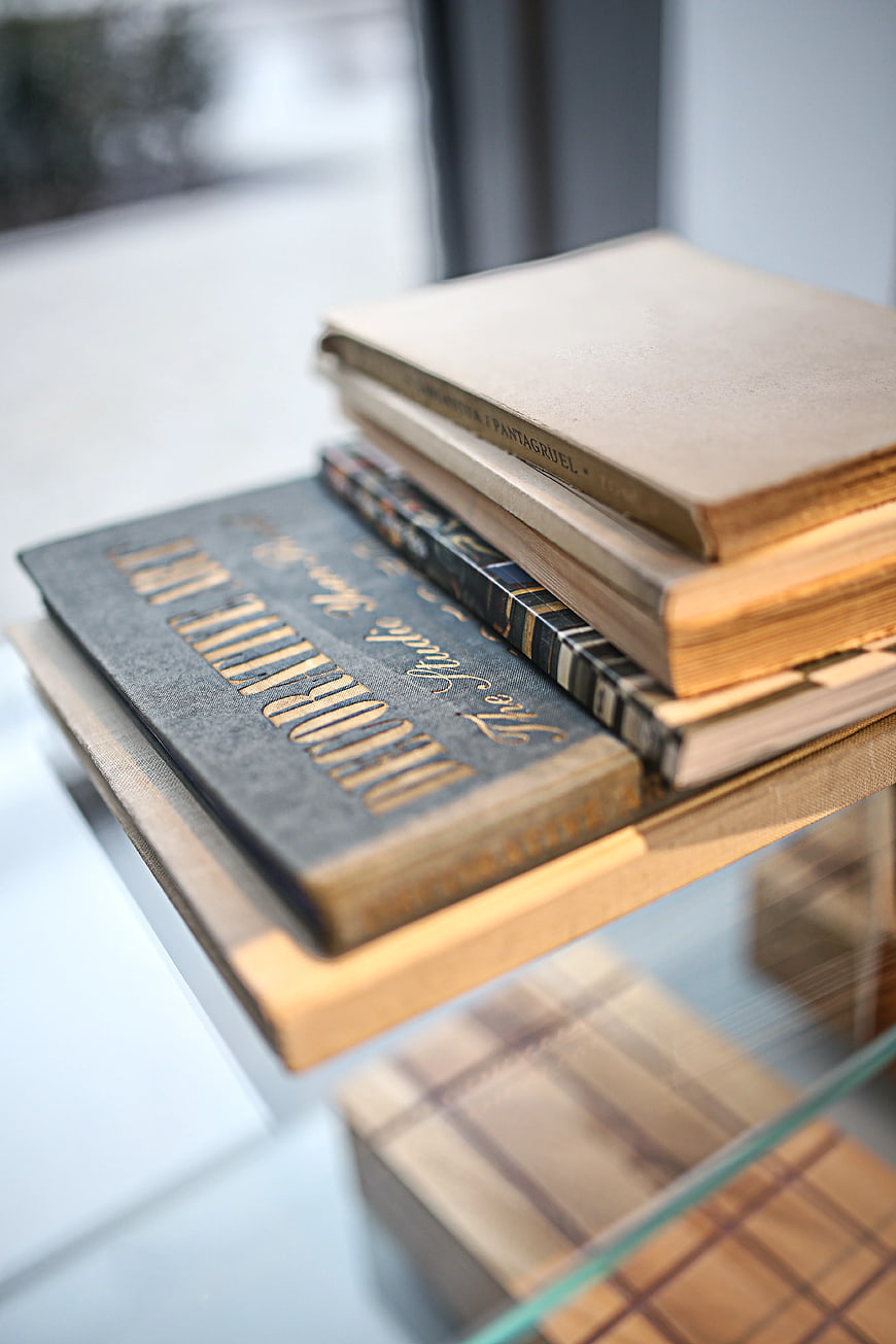 Stack of vintage books with gold lettering on glass shelf