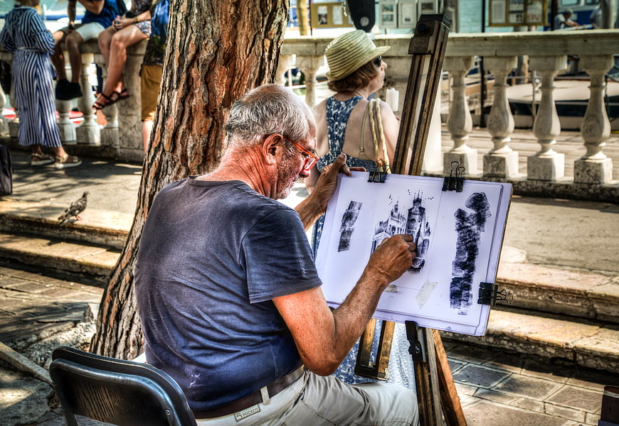 Senior artist sketching architecture on easel in Venice