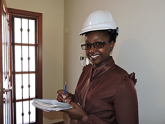 Smiling female engineer with hard hat and notebook in office
