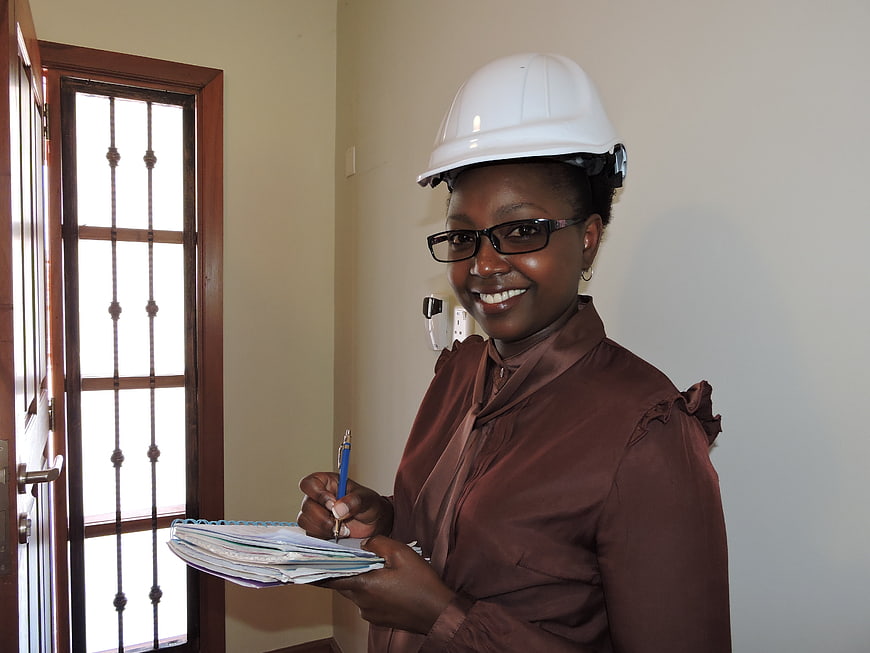Smiling female engineer with hard hat and notebook in office