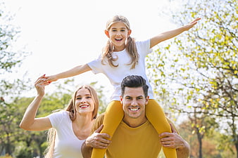 Happy Family with Daughter on Father's Shoulders in Park