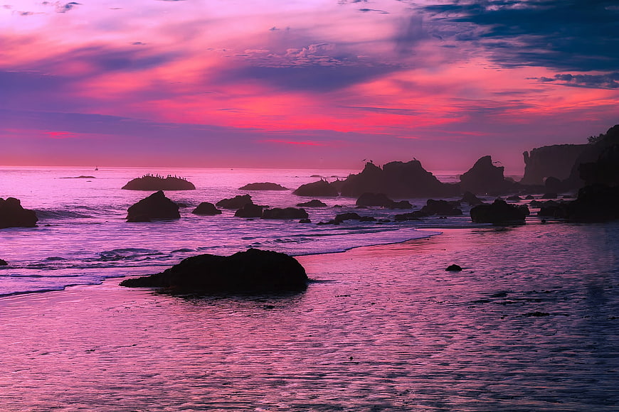Vibrant Pink Sunset Over Rocky Coastal Ocean Landscape