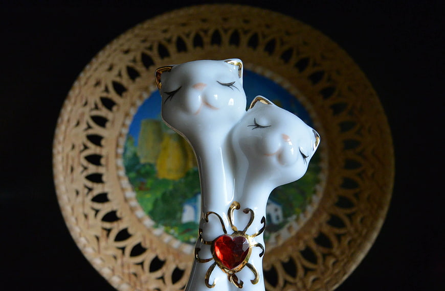 Close-up of white porcelain cat figurines with red heart