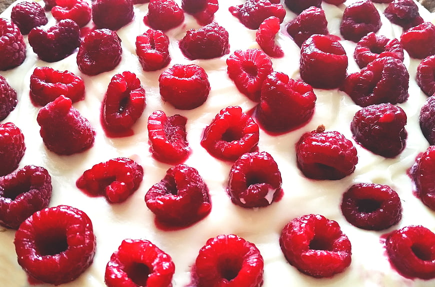 Close-up of fresh raspberries on white cream dessert