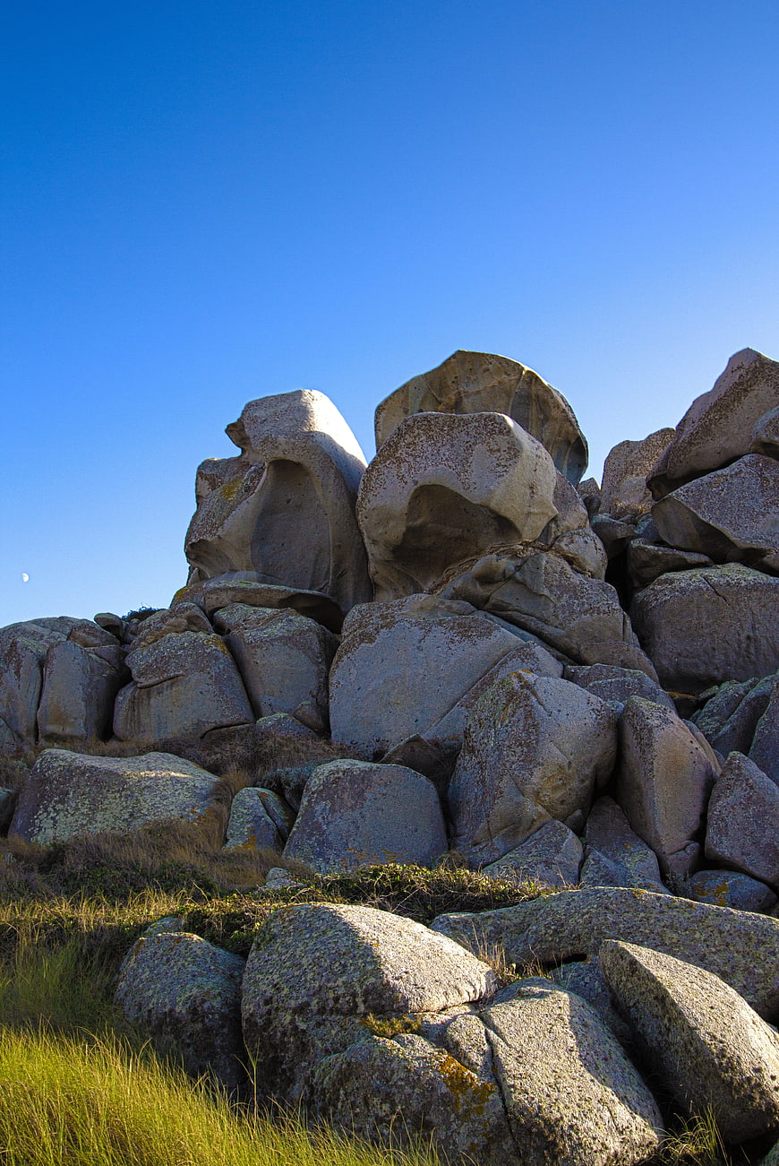 Granite Rock Formation on Grassy Hill Under Blue Sky