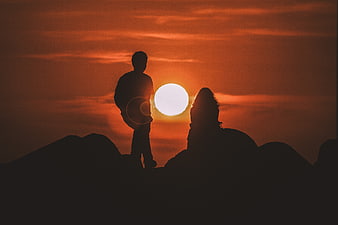 Silhouette of couple watching sunset on mountain