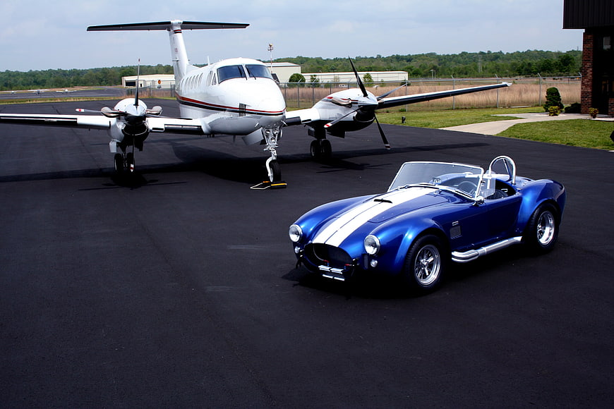 Blue Shelby Cobra and White Private Jet on Airport Tarmac