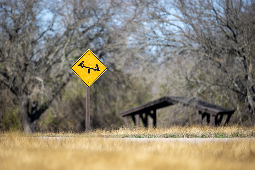 Yellow playground warning sign with seesaw symbol in park