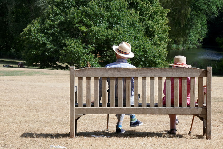 Senior couple sitting on park bench in summer