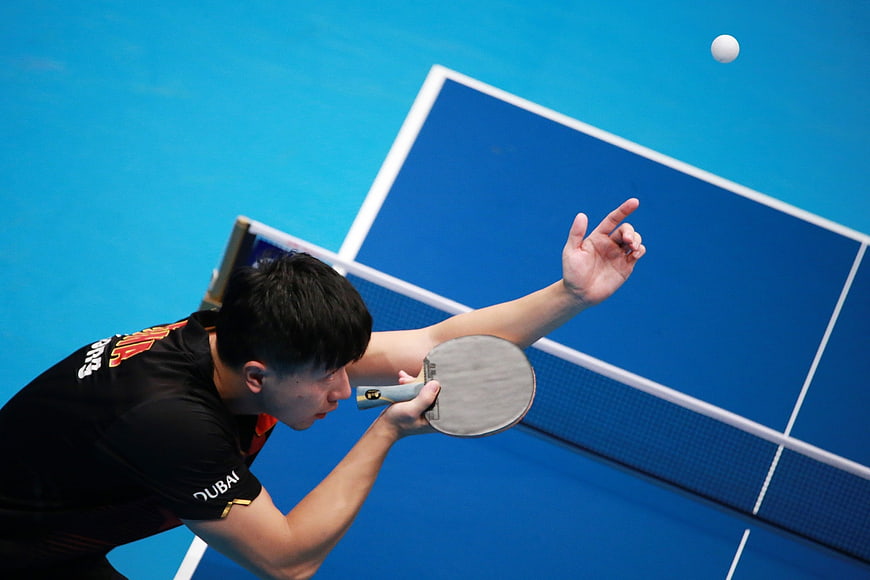 Table Tennis Player Serving Ball on Blue Court