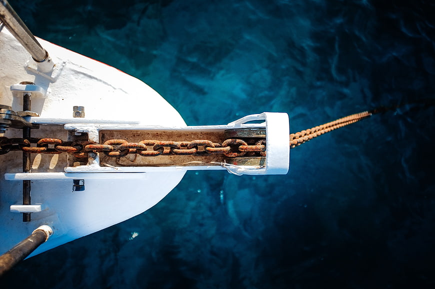 Rusty Anchor Chain On White Boat Bow Against Turquoise Sea
