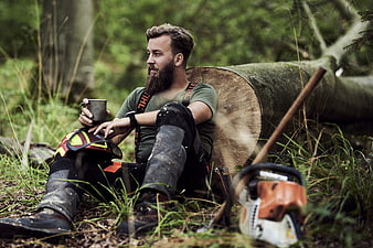 Bearded Lumberjack Resting in Forest with Chainsaw