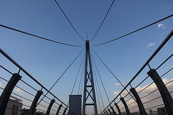 Low angle view of cable-stayed bridge tower against blue sky