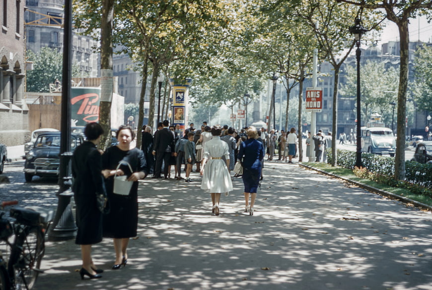 Vintage street scene with pedestrians walking on a tree-lined sidewalk
