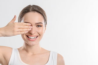 Happy Young Woman Covering One Eye with Hand