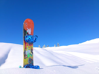 Colorful Snowboard Standing Upright in Snowy Landscape Under Blue Sky