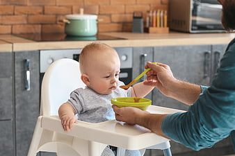 Father Feeding Baby in High Chair with Spoon