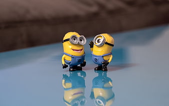Two Minion figurines standing on a reflective blue surface