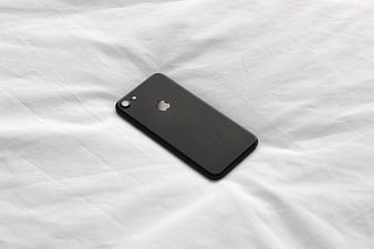 Black iPhone on White Bed Sheet Background