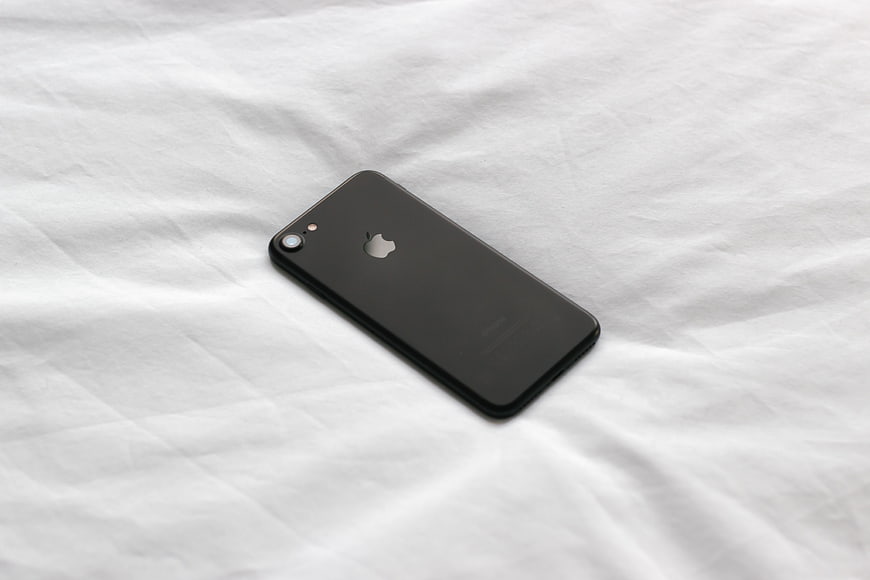 Black iPhone on White Bed Sheet Background