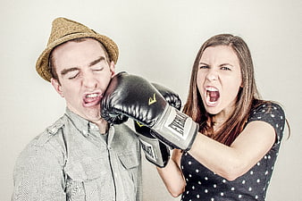 Angry woman punching man in face with boxing gloves