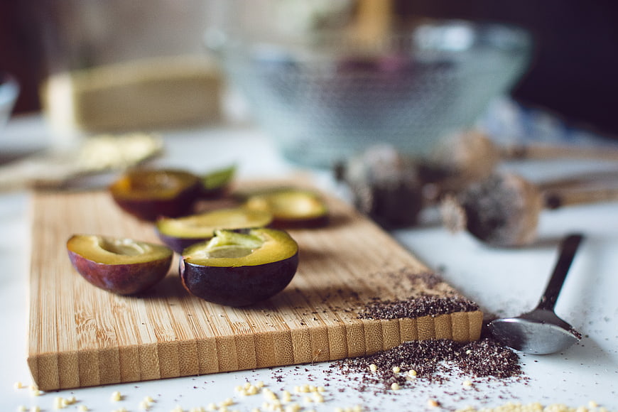 Fresh sliced plums on wooden cutting board with baking ingredients
