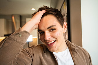 Smiling young man with hand on head in casual indoor setting