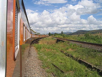 Orange train curving through rural landscape with blue sky