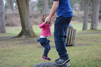 Father lifting daughter in the air at a park