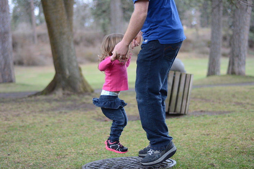 Father lifting daughter in the air at a park