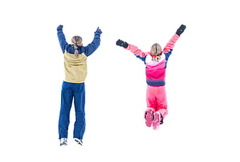 Two girls jumping in snow with arms raised
