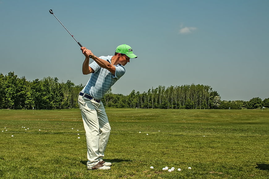 Male Golfer Completing Swing On Driving Range