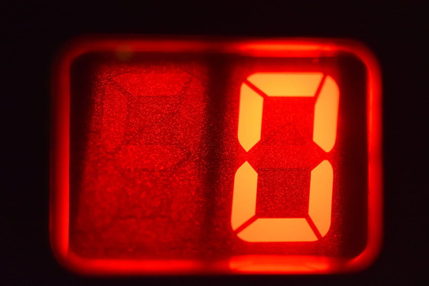 Close-up of glowing red digital number zero on dark display