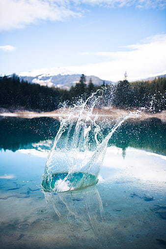 Crystal clear water splash in alpine lake with mountains