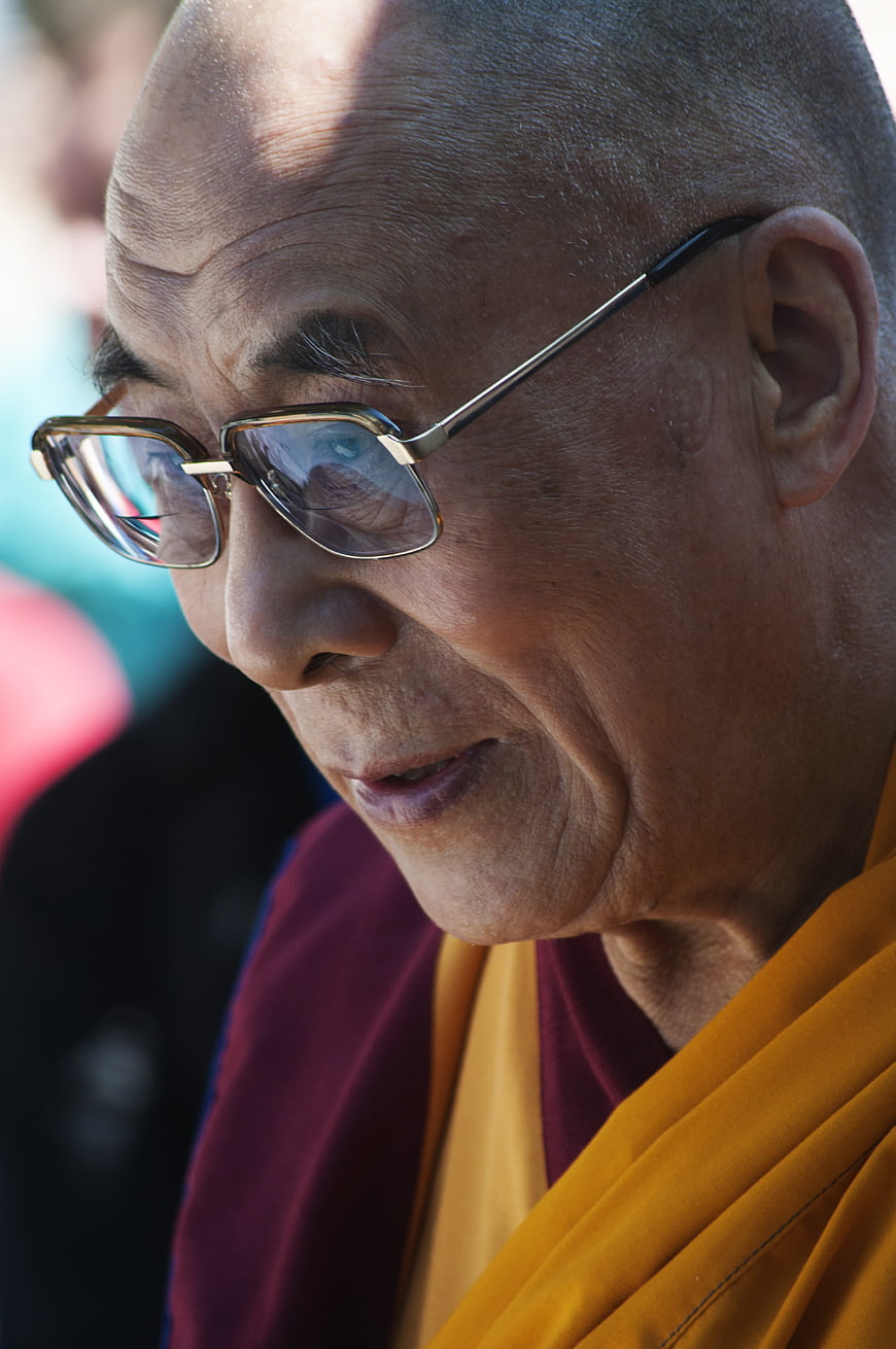 Close-up portrait of an elderly Tibetan Buddhist monk wearing glasses