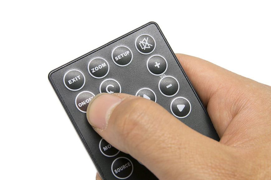 Hand Pressing Button On Black TV Remote Control