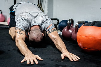 Sweaty Man Stretching in Gym with Kettlebells
